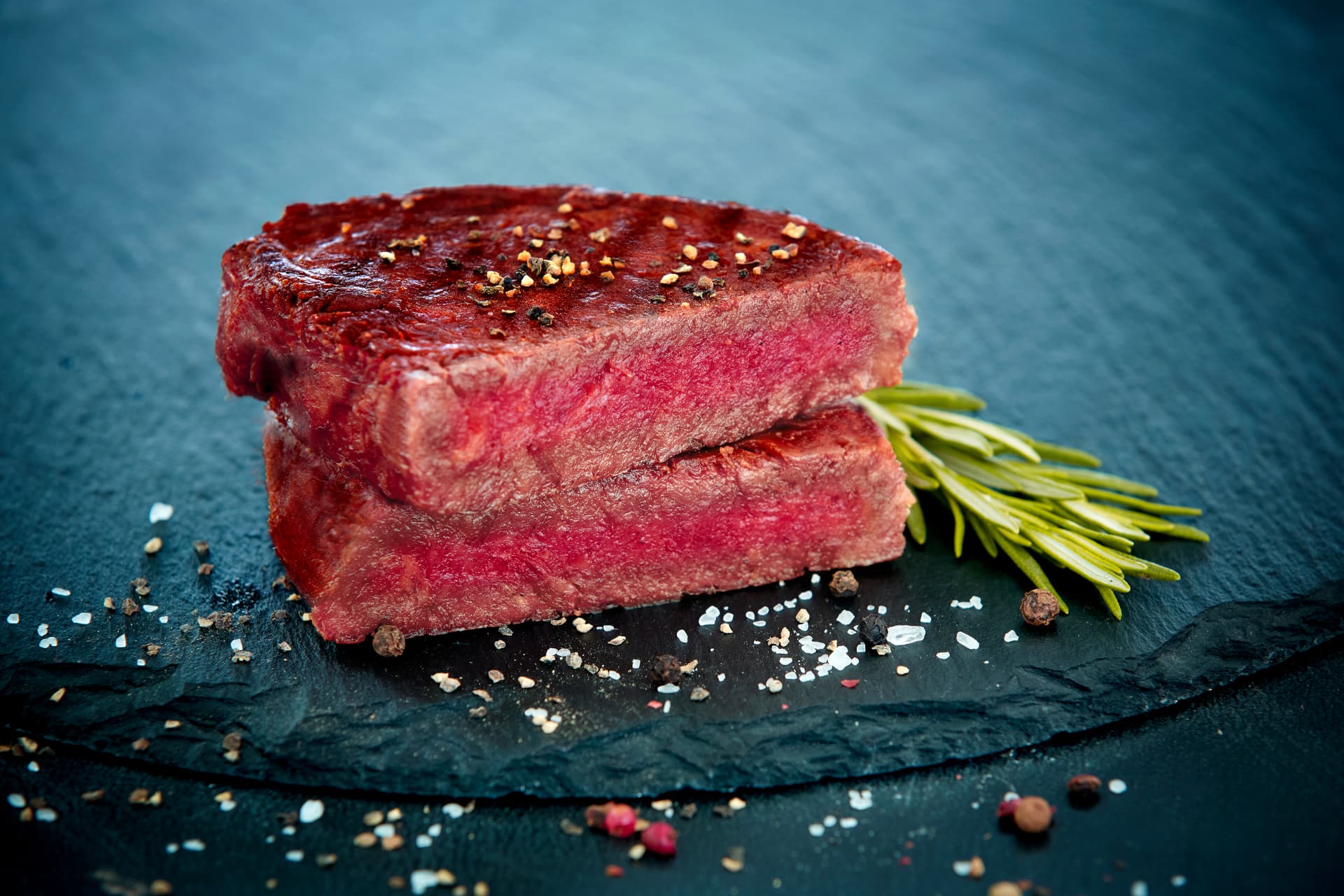 Two seared Offbeast hybrid steaks with rosemary and seasoning